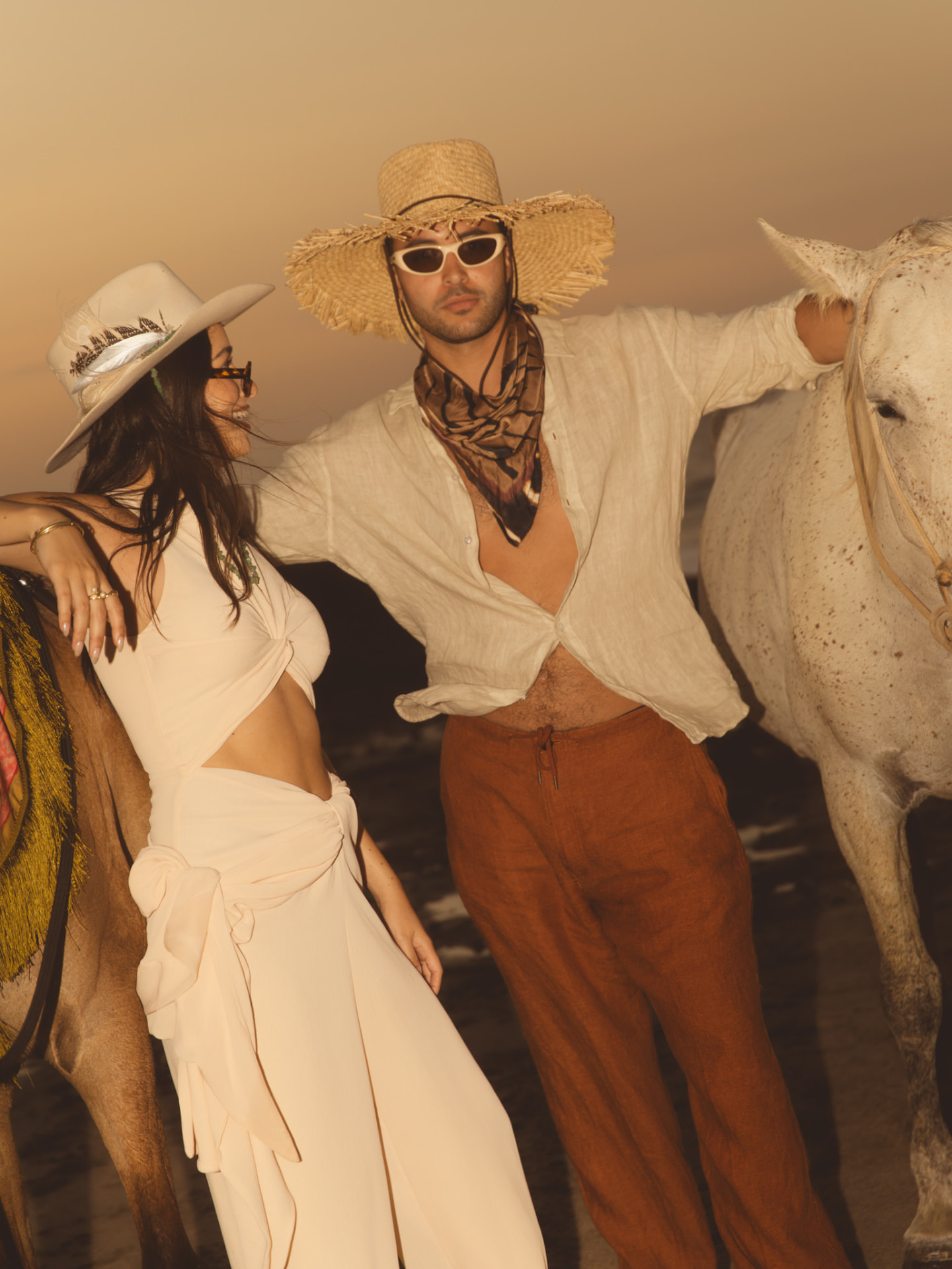 The couple on the beach with horses at sunset